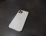 Elegancki, biały iPhone 12 Pro Max z charakterystycznym modułem aparatów na ciemnym tle.