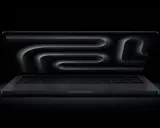 MacBook Pro z polskim układem klawiatury, ciemny ekran z abstrakcyjnym wzorem.