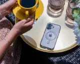 Eleganckie etui przezroczyste z wzorami na telefon, leżące obok żółtej filiżanki kawy i białych kwiatów.