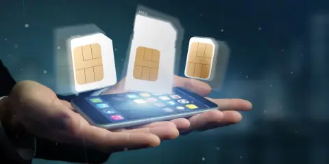 Dłoń trzyma smartfon, nad którym unoszą się karty SIM. Dowiedz się, jak zarejestrować kartę SIM Plus.