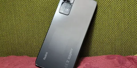 Elegancki, szary Redmi Note 11 Pro 5G Plus z aparatem 108MP na tle zielonej i bordowej tkaniny.