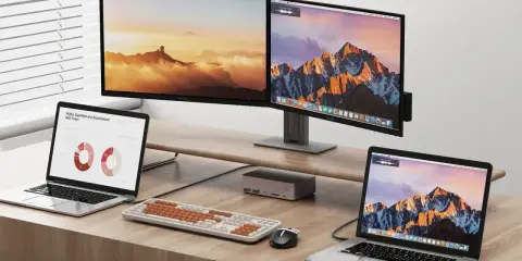 Dwa monitory i dwa laptopy na biurku. Dowiedz się, jak podłączyć dwa monitory do laptopa z jednym HDMI, używając stacji dokującej.