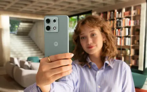 Kobieta robi selfie telefonem Motorola E6 Play w nowoczesnym wnętrzu.