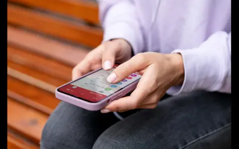 Dłonie kobiety obsługują smartfon, który wyświetla listę e-maili. To przykład interakcji, która może wykorzystywać haptykę – co to za technologia?