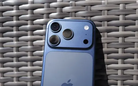 Niebieski iPhone 11 z potrójnym aparatem z tyłu, leżący na plecionej powierzchni.