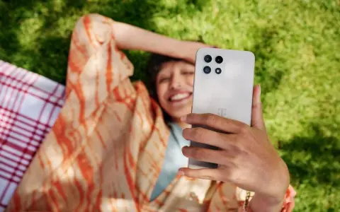 Uśmiechnięta osoba robi selfie na trawie, ciesząc się czasem przed ekranem.