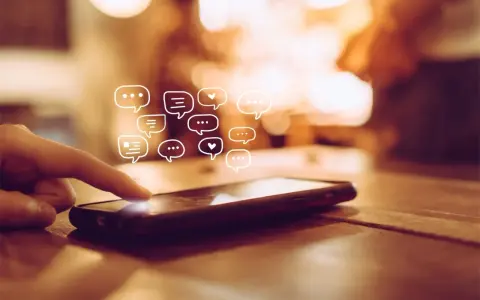 Palec dotyka ekranu telefonu, a nad nim pojawiają się dymki czatu. Dowiedz się, jak odzyskać wiadomości z kosza w telefonie.