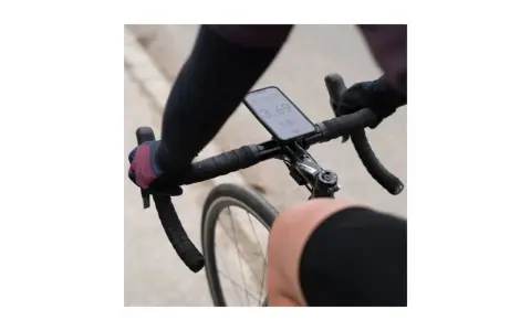 Rowerzysta trzyma kierownicę, na której zamontowano telefon za pomocą uchwytu sp connect. Na ekranie widoczny czas i prędkość.