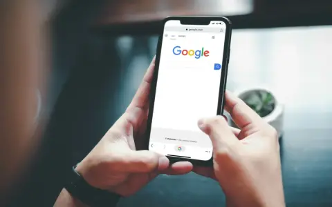 Ręce trzymające smartfon z otwartą wyszukiwarką Google. Szukasz informacji, jak usunąć konto Google z telefonu po resecie?