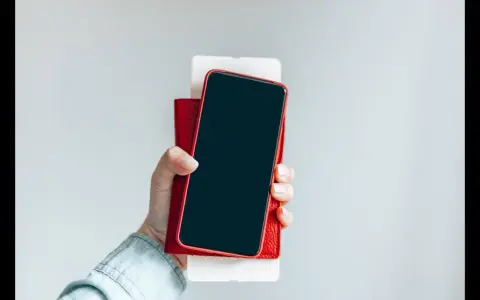 Dłoń trzyma iPhone'a w czerwonym etui. Czy iPhone jest bezpieczny? Zależy od użytkownika i jego nawyków.