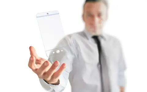 Mężczyzna w białej koszuli i krawacie trzyma w dłoni przezroczysty telefon, symbol przyszłości technologii.
