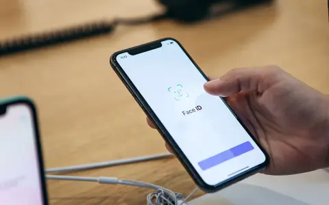 Dłoń trzyma iPhone'a z włączonym ekranem Face ID.