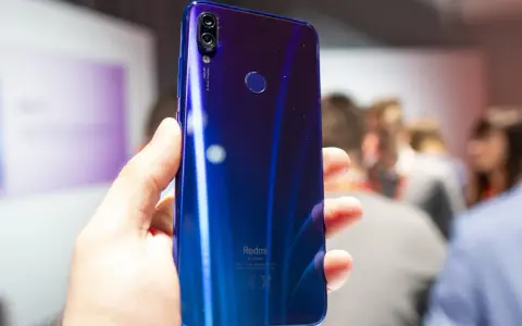 Błyszczący, niebieski tył telefonu Redmi 7 Pro z podwójnym aparatem 48MP i czytnikiem linii papilarnych, trzymany w dłoni.